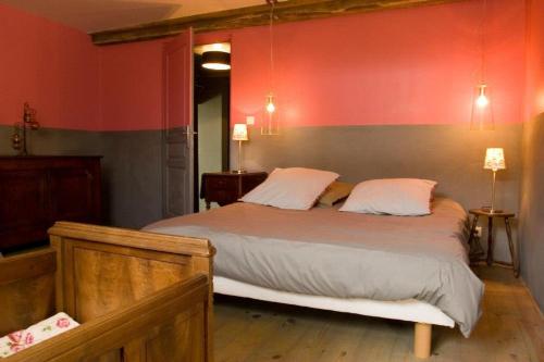 a bedroom with a large bed with red walls at Les Roussis in Saint-Germain-des-Champs