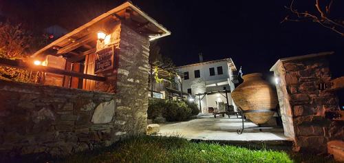 a building with a large vase next to a building at night at Archontiko Mansion Porteli Αρχοντικο Πορτελι in Makrinítsa