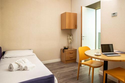 Residence Portello في ميلانو: غرفة مع سرير وطاولة مع لاب توب