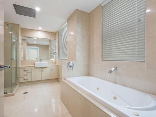 y baño con bañera, lavabo y espejo. en Solaya Unit 6, en Gold Coast