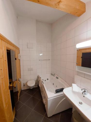 a bathroom with a tub and a toilet and a sink at Walensee House & Apartments in Unterterzen