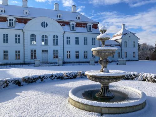a fountain in the snow in front of a large building at Schloß Vietgest in Vietgest