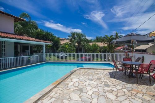 a swimming pool with a table and chairs next to a house at Pousada Três Pescadores in Búzios