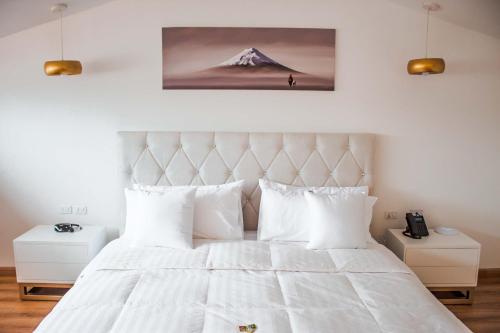 a bedroom with a large white bed with white pillows at Adamas House Hotel Boutique in Quito