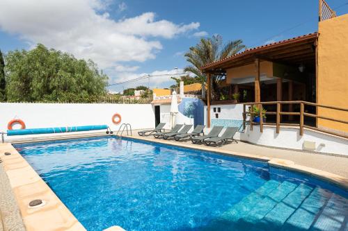 a swimming pool with chairs and a house at Villa la Atlantida in Ingenio