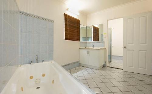 y baño con bañera, lavabo y espejo. en Coral Sands Motel en Mackay