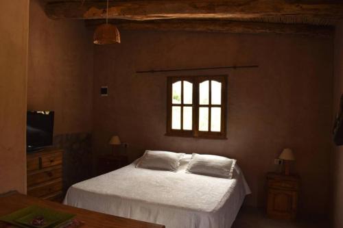 1 dormitorio con 1 cama con sábanas blancas y ventana en Ruphay: Cabaña equipada con vista a los cerros en el campo en Maimará