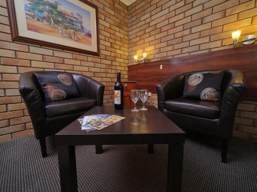 una habitación con 2 sillas de cuero y una mesa con una botella de vino en City View Motel, en Warwick