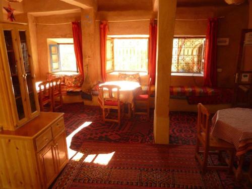 a room with a table and chairs and windows at Auberge Ayouze in Aït Ben Haddou