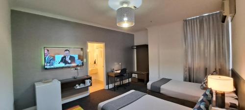 a hotel room with a bed and a tv on a wall at Criterion Hotel Perth in Perth