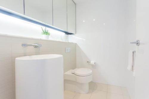 a white bathroom with a toilet and a sink at Oracle Resort Broadbeach - gclr in Gold Coast
