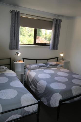 two beds in a room with a window at Altona Garden Retreat in Spreyton