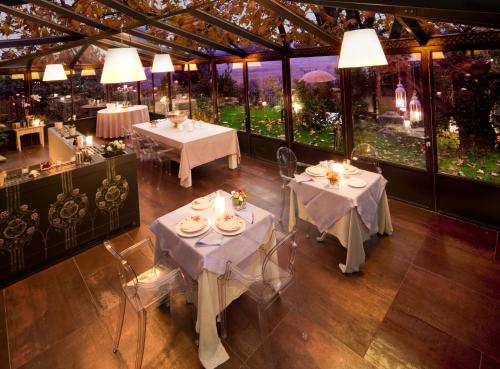 a restaurant with white tables and chairs and windows at Relais La Magioca -Adults Only- in Negrar