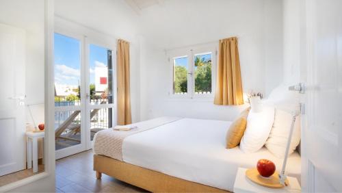 a white bedroom with a bed and a balcony at Almyrida Sands in Almirida