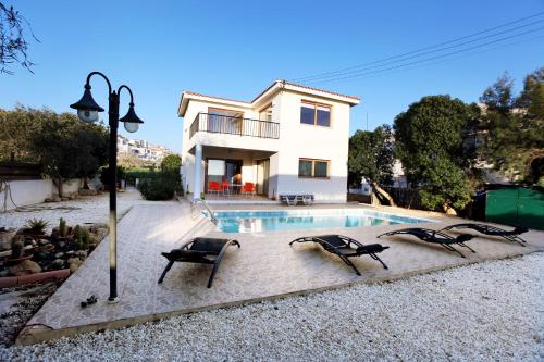 a villa with a swimming pool in front of a house at Villa Elina in Paphos City