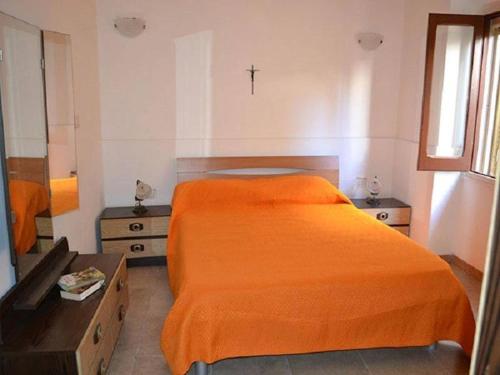 um quarto com uma cama laranja e uma cruz na parede em Three-room holiday home with outdoor space and a few steps from the cliff em Torre dell'Orso