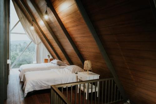 two beds in a room with a large window at villa tibra in Lembang