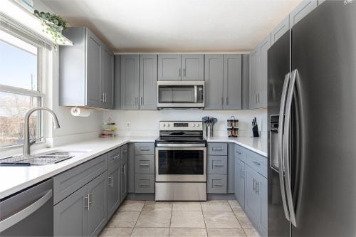 a kitchen with white cabinets and a stainless steel refrigerator at Well-Stocked, Family Friendly Home on the Westside STR-1669 in Colorado Springs