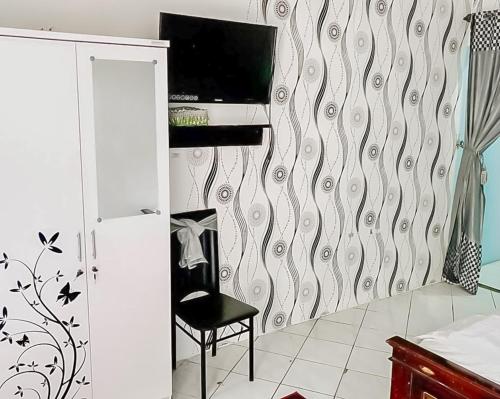a room with a chair and a television on a wall at Homestay Levida Mitra RedDoorz in Samarinda