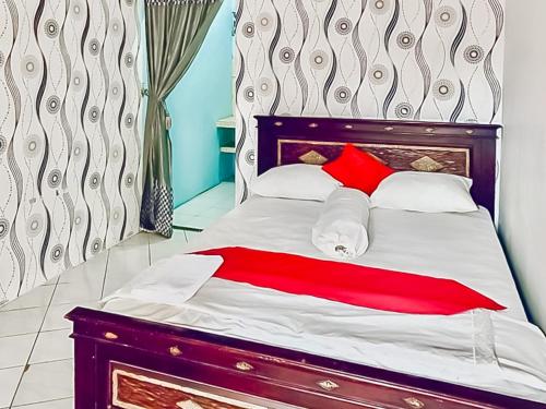 a bedroom with a bed with red and white pillows at Homestay Levida Mitra RedDoorz in Samarinda