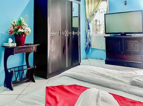 a bedroom with a bed and a tv and a table at Homestay Levida Mitra RedDoorz in Samarinda