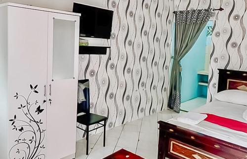 a bedroom with a bed and a chair in it at Homestay Levida Mitra RedDoorz in Samarinda