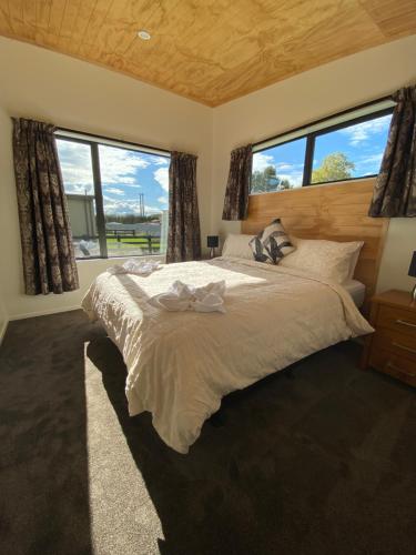 a bedroom with a large bed with two windows at Country Retreats on Ranzau 3 in Nelson