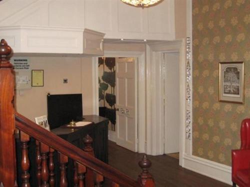 a living room with a staircase and a desk with a television at Canterbury Hotel Cottages and Apartment's in Canterbury