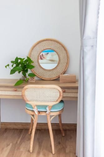 a wicker chair sitting in front of a desk with a mirror at Rivera Tuy Hòa Hotel in Tuy Hoa