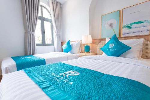a hotel room with two beds with blue and white at Rivera Tuy Hòa Hotel in Tuy Hoa