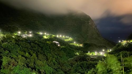a view of a mountain at night with lights at Jiufen Gourd Stone TreeHouse 137 in Ruifang