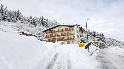 una carretera cubierta de nieve frente a un edificio en Appartamenti La Val en Andalo