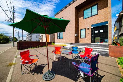 a table with chairs and an umbrella in front of a building at THE WORLDWIDE HOUSE in Sapporo