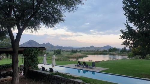 a swimming pool with chairs and a view of a lake at Big Sky Ranch in Colesberg