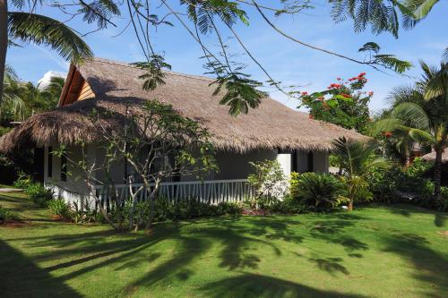 a house with a thatched roof and a yard at The Cliff Resort & Residences in Mui Ne
