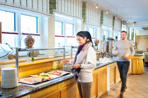 a man and a woman standing in a kitchen preparing food at Hotel Zehnerkar & Hotel Obertauern in Obertauern