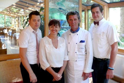 une femme et trois hommes debout dans un restaurant dans l'établissement Art Hotel Kristal, à Bohinj