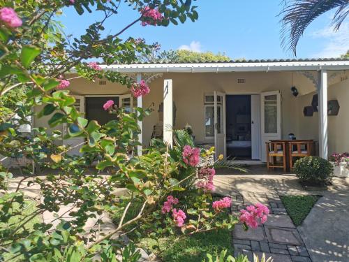 a cottage with pink flowers in the yard at Eight Palms in Port Edward