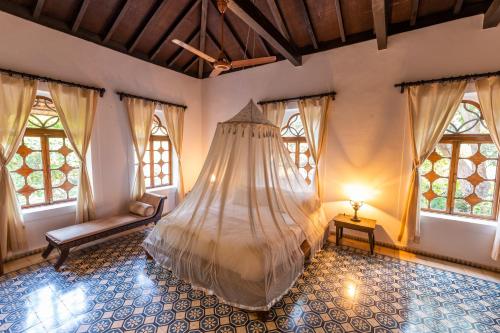 a bedroom with a bed in a room with windows at Marbella Guest House in Sinquerim