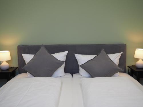 a bedroom with a bed with two pillows and two lamps at LOK - Die Pension - Das Restaurant in Tessin
