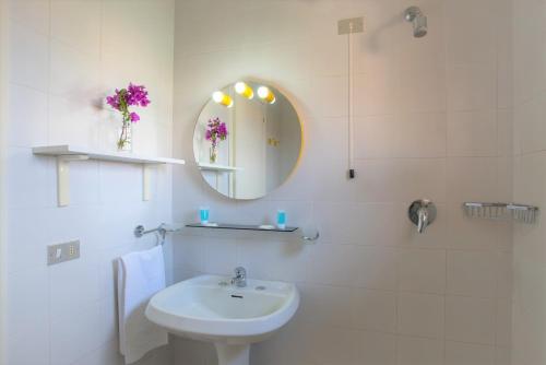 bagno bianco con lavandino e specchio di Residence Bouganville a Porto Rotondo