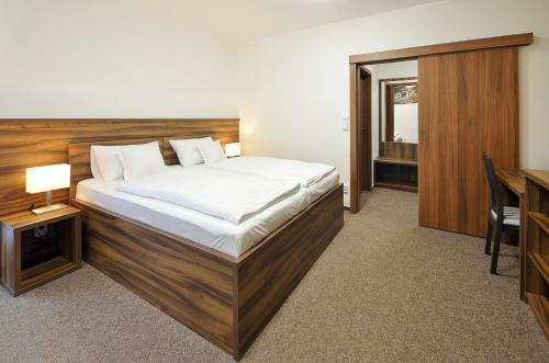 - une chambre avec un grand lit et un bureau dans l'établissement Penzion Kuželna, à Trutnov