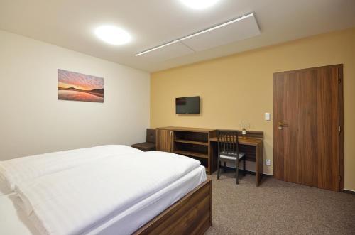 a bedroom with a bed and a desk and a television at Penzion Kuželna in Trutnov