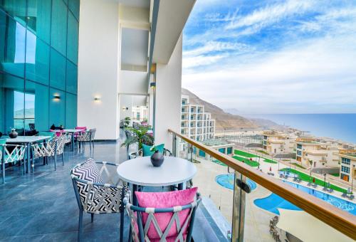 a balcony with tables and chairs and a view of the ocean at Tolip Resort El Galala Hills in Ain Sokhna