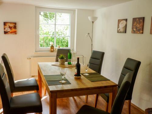 a dining room table with chairs and a bottle of wine at LandArt in Olpe