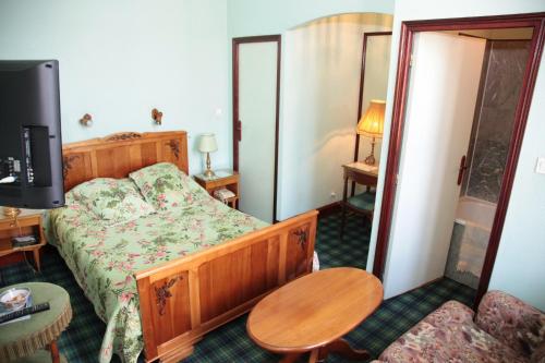 a bedroom with a bed and a tv and a table at Cit'Hotel Marie Stuart in La Roche-sur-Yon