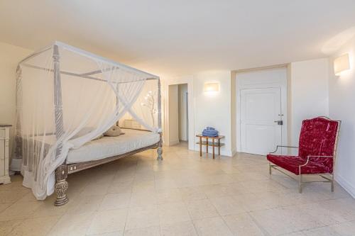 a bedroom with a canopy bed and a red chair at Casa Bormioli - Maison de Charme in Procida