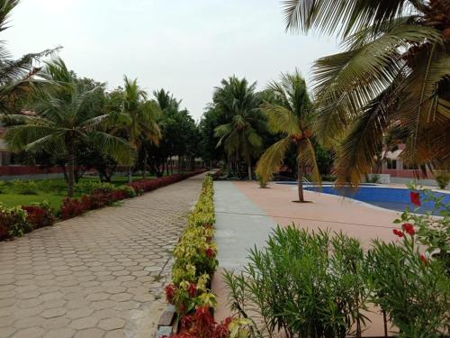 a cobblestone path in a park with palm trees and flowers at coral beach resort in Mahabalipuram