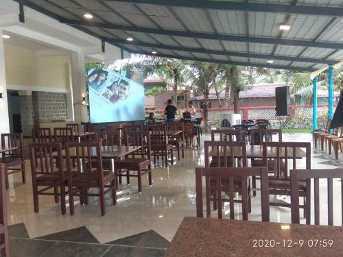 un restaurante con mesas, sillas y una pantalla en coral beach resort en Mahabalipuram