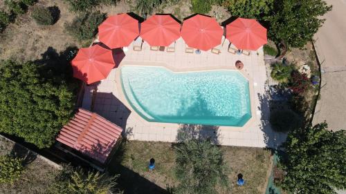 een uitzicht over een zwembad met rode parasols bij Hôtel des Vignes in Juliénas